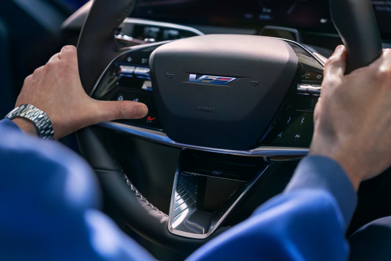 Close-up of a Man About to Press the V-Button on the 2026 OPTIQ-V Steering Wheel | Morris Cadillac in NORTH OLMSTED OH