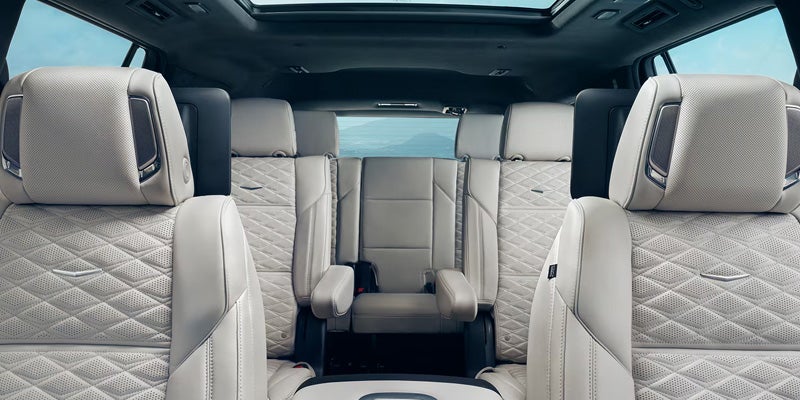 Interior view showing three rows of light gray diamond-quilted leather seats in a Cadillac Escalade SUV.